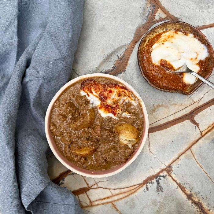 Hearty beef stew with potatoes and sour cream, gluten-free ready meal on marble surface