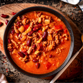 Hearty chili with ground meat, kidney beans, onions, and peppers in a rustic bowl, ready to eat.
