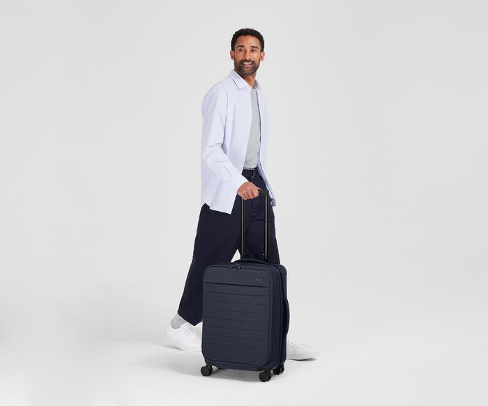 Person standing next to the Softside Bigger Carry-on for scale