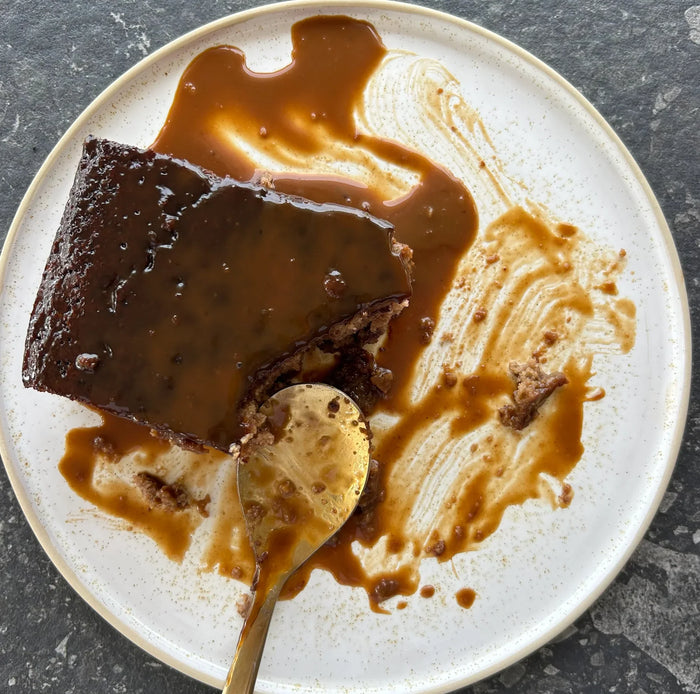 Half eaten slice of sticky date pudding with caramel sauce